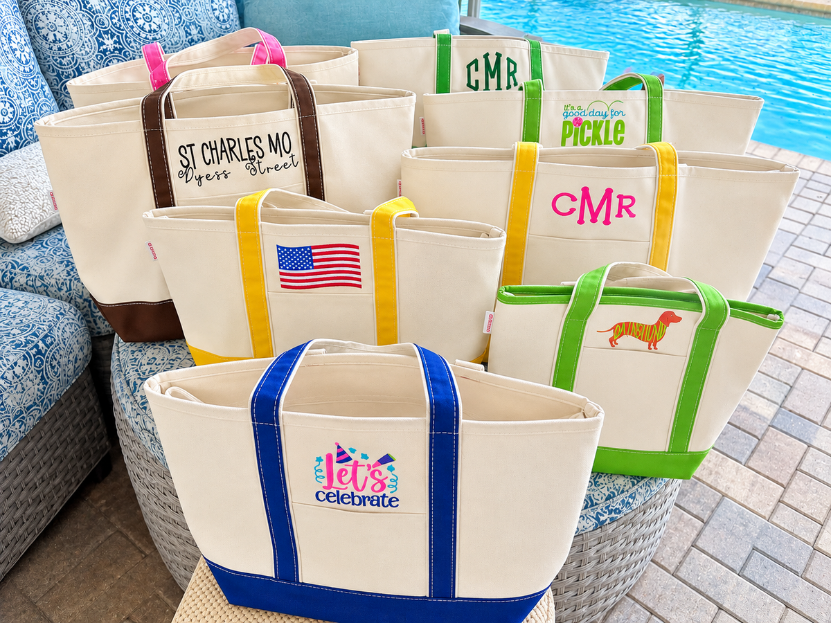 Colorful embroidered Florida Seaside Home canvas tote bags arranged beside a pool