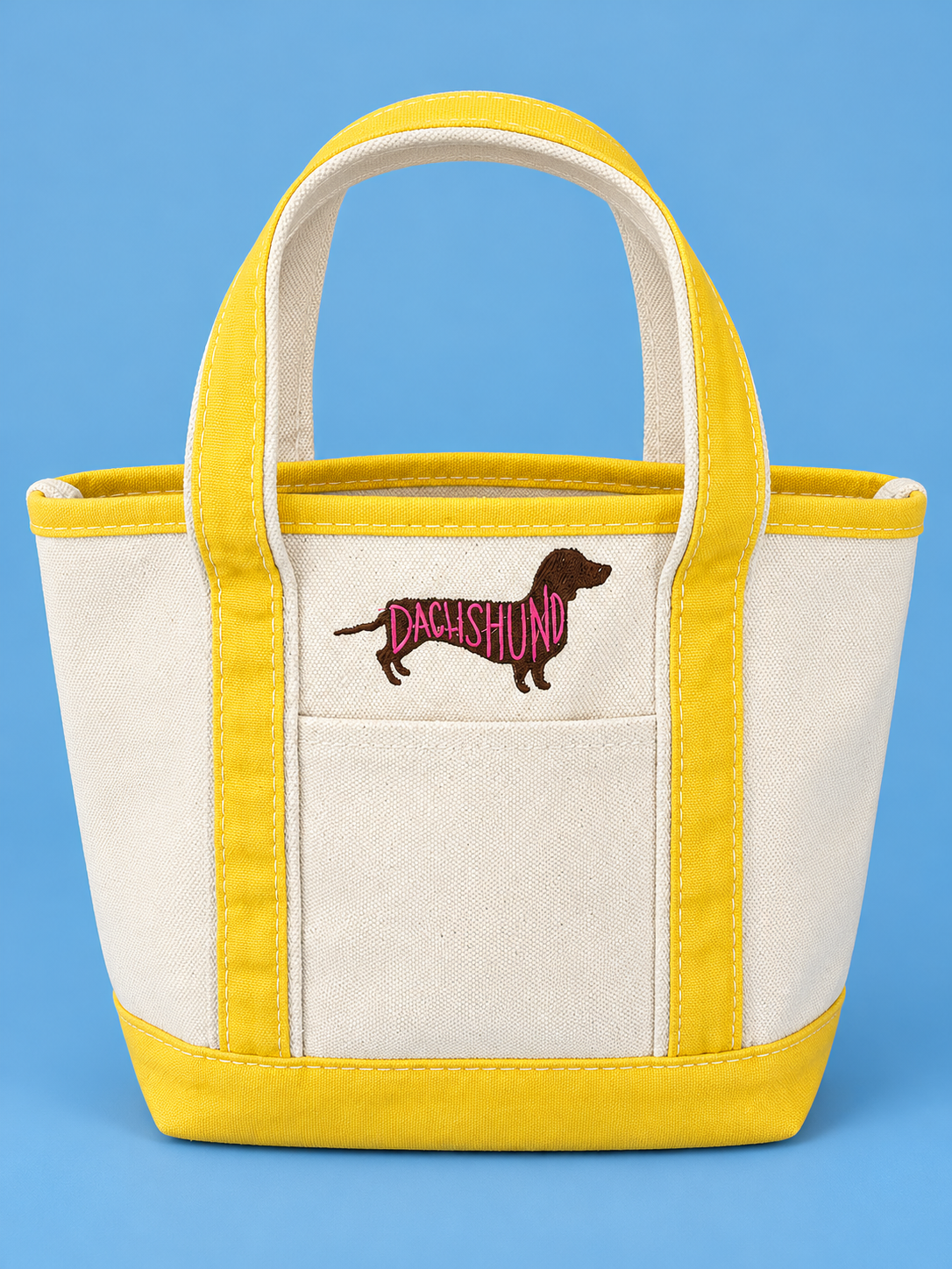 Yellow-trimmed mini canvas tote with dachshund embroidery on a Carolina blue background