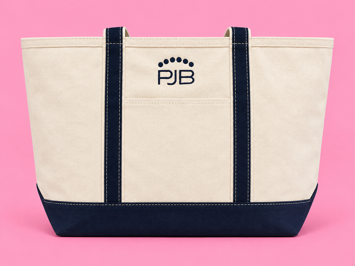 Cream and navy canvas tote with PJB embroidery on a bubblegum pink background