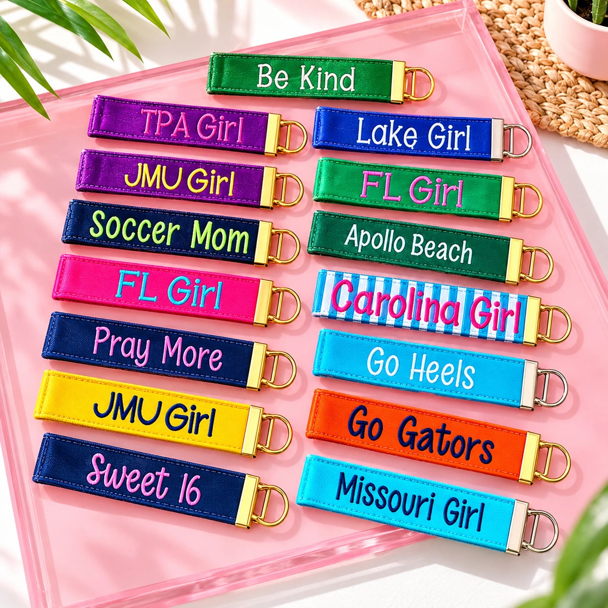 Colorful embroidered keychains displayed on a pink tray