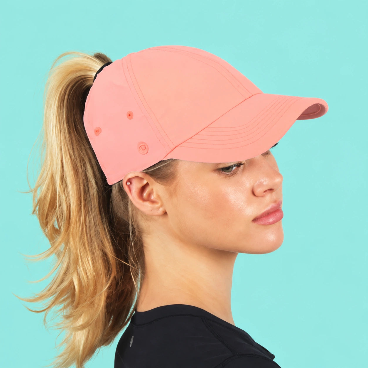 Peach Ponyflo ponytail hat against a fresh aqua background