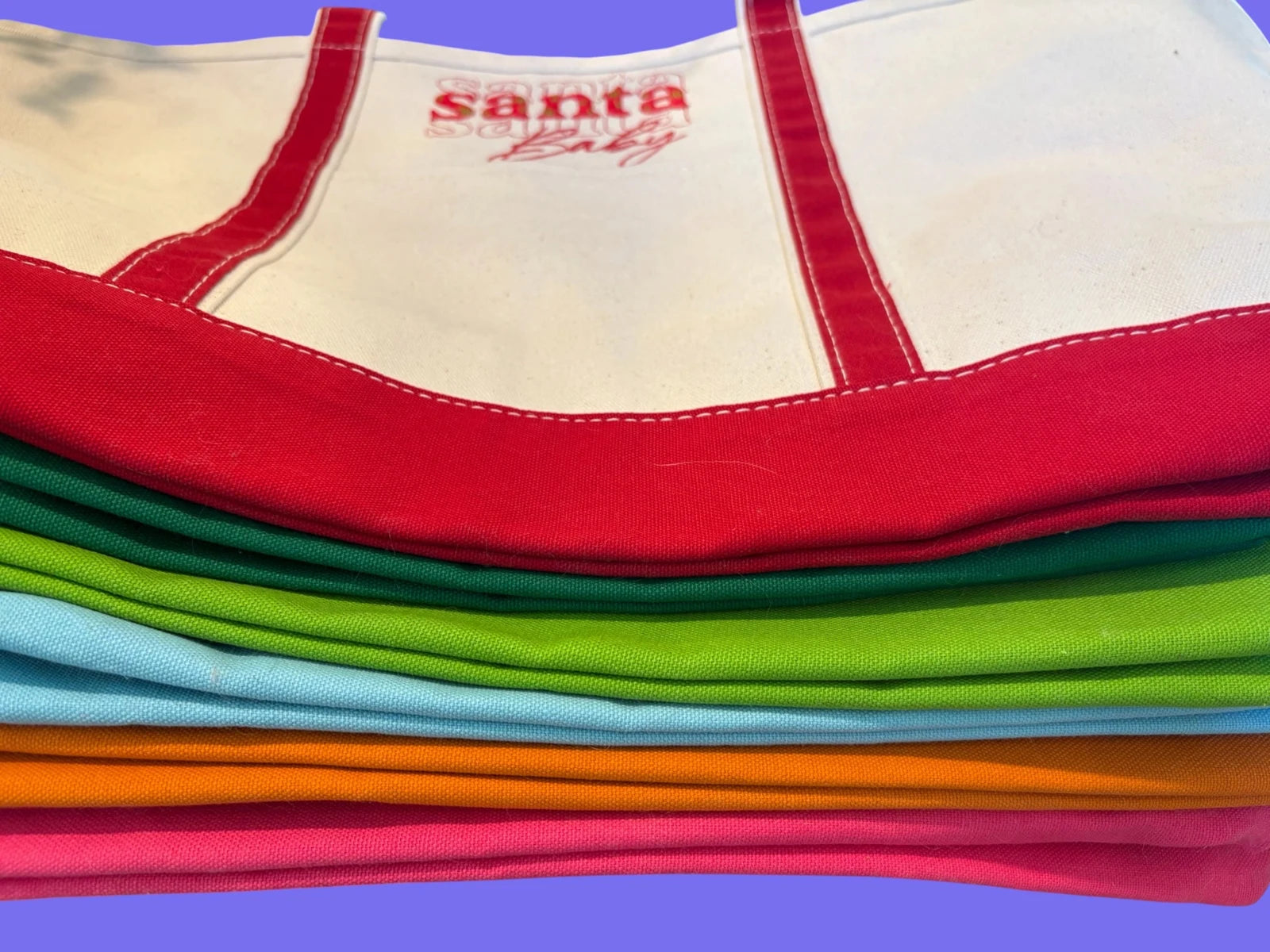 Stack of canvas totes showing red, green, lime, light blue, orange and pink trim